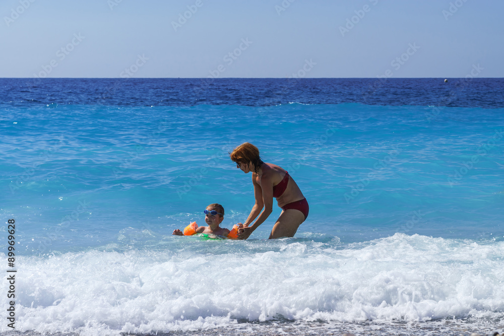 Cute little girl with her mother learning to swim