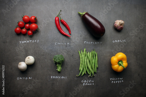 Fresh vegetables with chalky signs on grey kitchen table