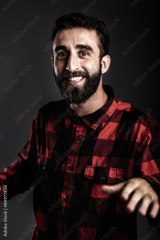 Fototapeta premium Portrait of a happy young man with beard, dancing against gray b