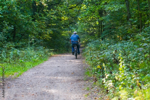 Man riding on bike through summertime forest