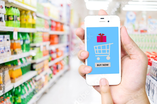 Hand holding smart phone over blur supermarket background