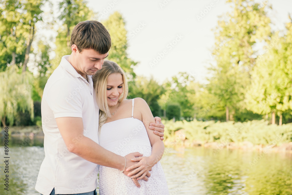 Man hugging his pregnant wife in the city park.