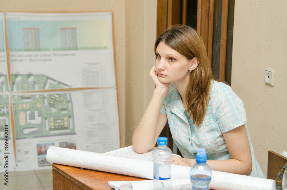 Sad student sitting at desk with drawings Sad student sitting at desk with drawings