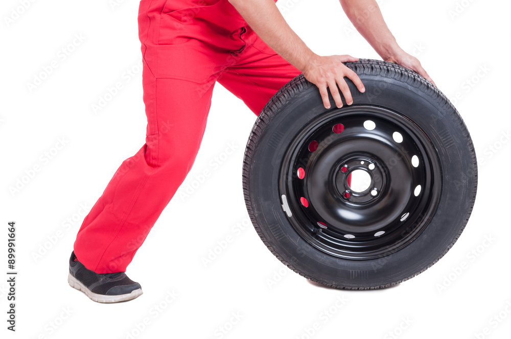 Mechanic pushing car wheel on white background Mechanic pushing car wheel on white background