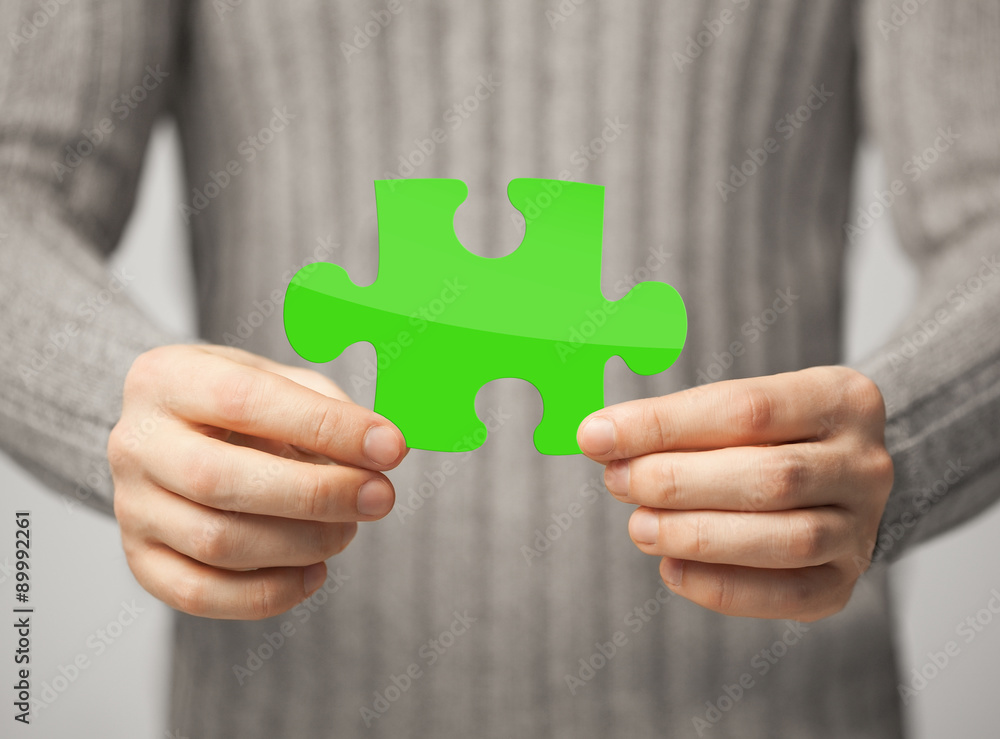 close up of man holding green puzzle piece close up of man holding green puzzle piece
