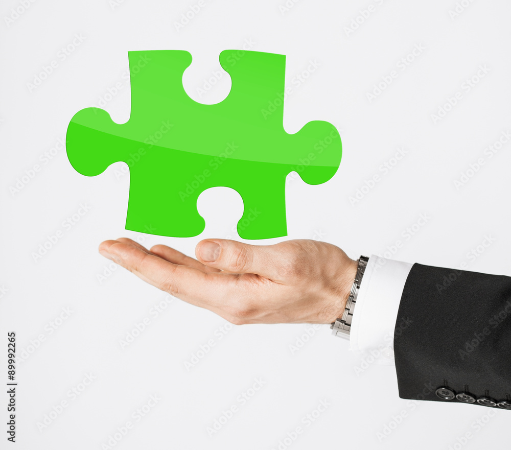 close up of man holding green puzzle piece close up of man holding green puzzle piece