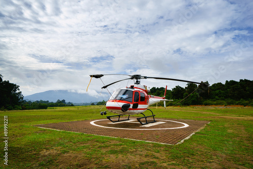 Helicopter parked at the helipad near forest photo