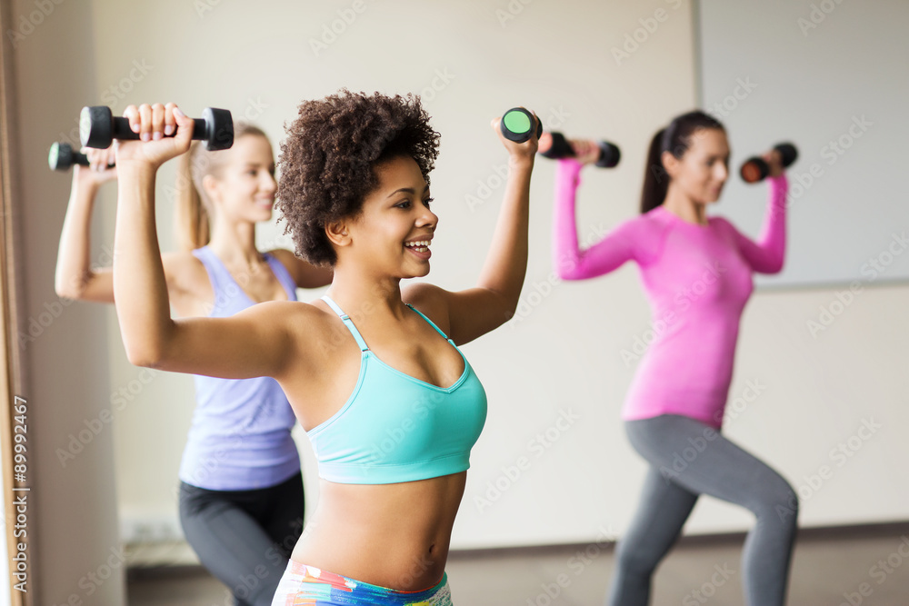 group of happy women with dumbbells in gym group of happy women with dumbbells in gym
