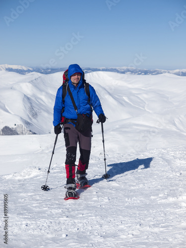 A man with a backpack and snowshoes.