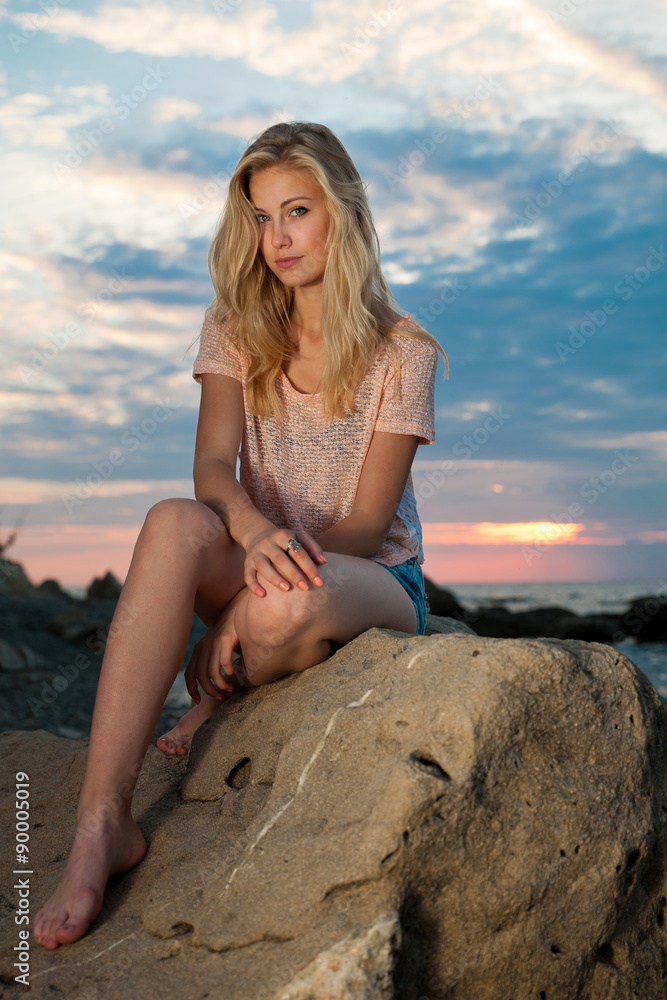 Beautiful young blonde woman resting on a beach at dusk in early Beautiful young blonde woman resting on a beach at dusk in early