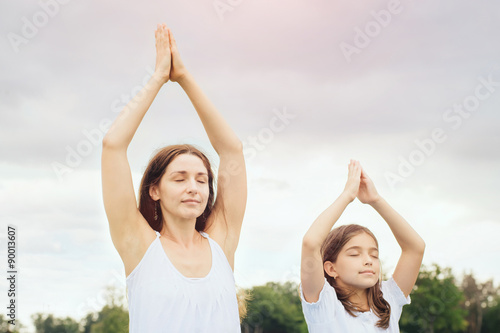 Mother with daughter doing yoga exercise