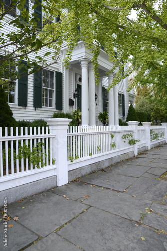 white picket fence by a typical federal style house