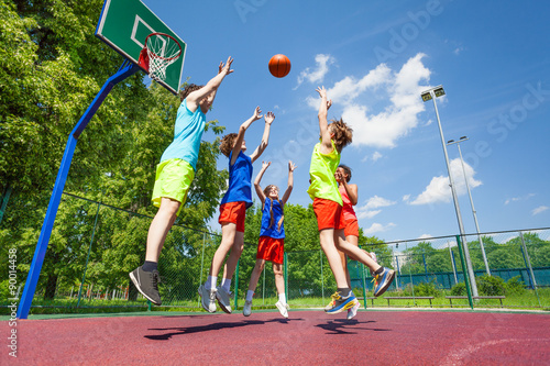 Children jump for flying ball during basketball