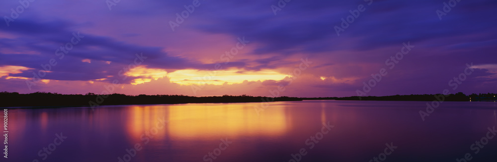 This is the ocean and Pine Island at sunset. There is a pinkish purple cast in the sky that is reflected in the water. The nearby land is in silhouette.