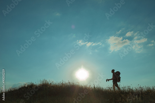 Young caucasian man with backpack walking on a green meadow