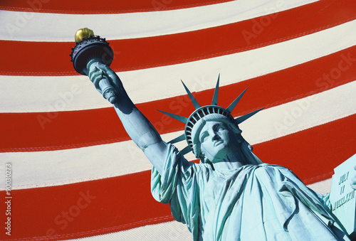 This is a digitally created image of the Statue of Liberty. The statue is the top part of her body with arm and torch coming form the right hand corner of the image. The background has the red and white stripes of the American flag.