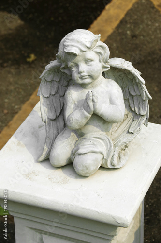 close up cement cherub doll in garden
