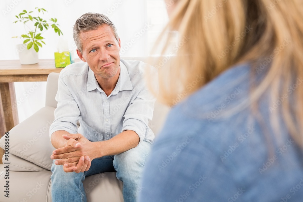 Worried man sitting on couch and talking to therapist Worried man sitting on couch and talking to therapist