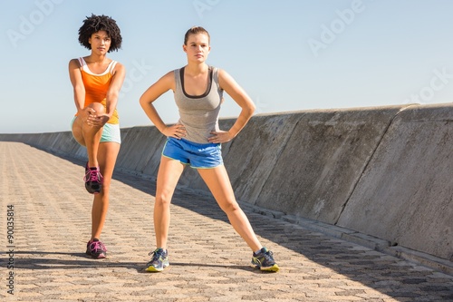 Two young woman stretching together