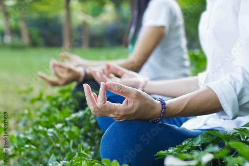 women meditating outdoors in green park on nature background