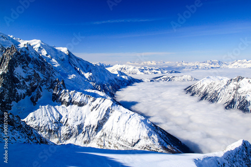Fog flows in a snowy valley between mountains