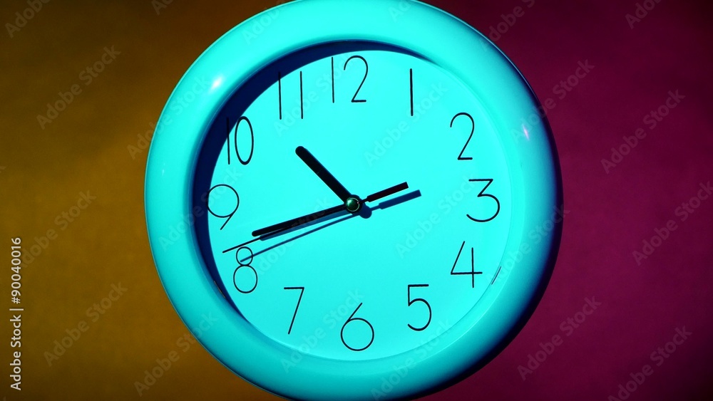 Simple clock or watch on white tile wall displaying one o'clock Stock