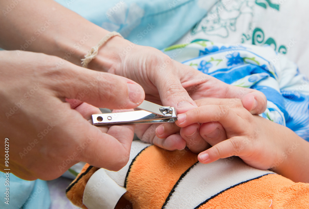 Mother cutting daughter 's nails using the clippers