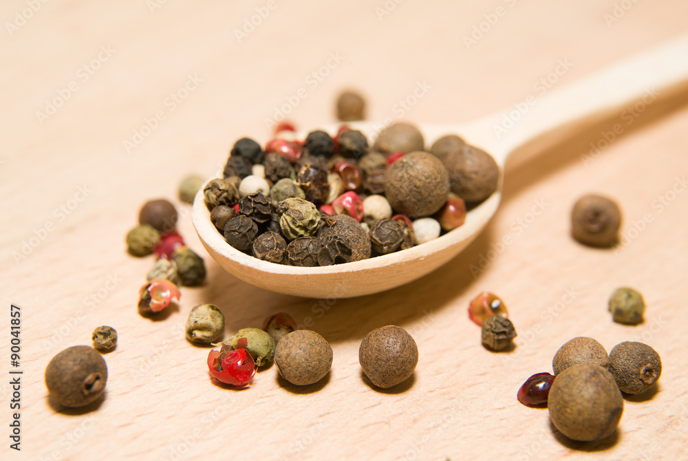 Spoon filled with grains of pepper on a wooden surface Spoon filled with grains of pepper on a wooden surface