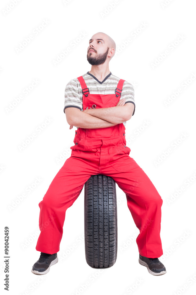 Mechanic sitting on car wheel isolated on white Mechanic sitting on car wheel isolated on white
