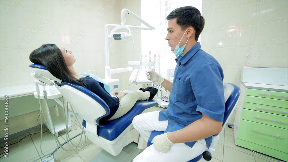 The dentist closer to patient sitting in the dental chair and The dentist closer to patient sitting in the dental chair and