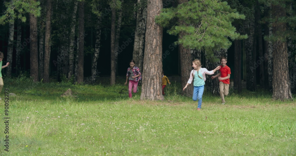 Playful kids hiding behind tree trunks and then running joyfully towards the camera Playful kids hiding behind tree trunks and then running joyfully towards the camera