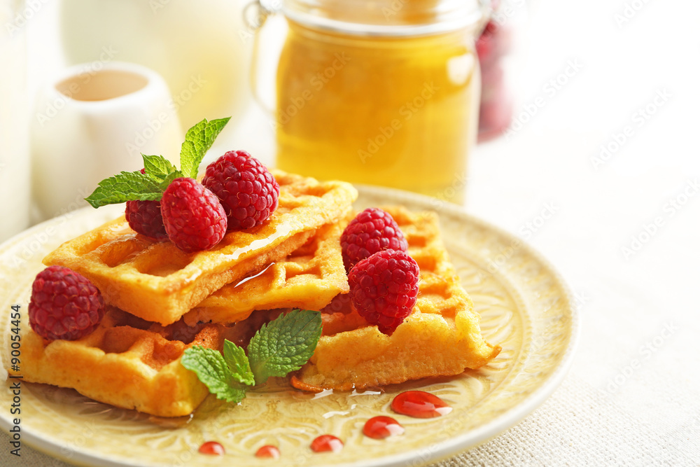 Sweet homemade waffles with fresh raspberries on plate, on light background Sweet homemade waffles with fresh raspberries on plate, on light background