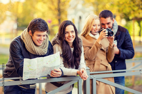 group of friends with map and camera outdoors