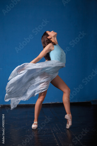 young modern ballet dancer posing on blue background