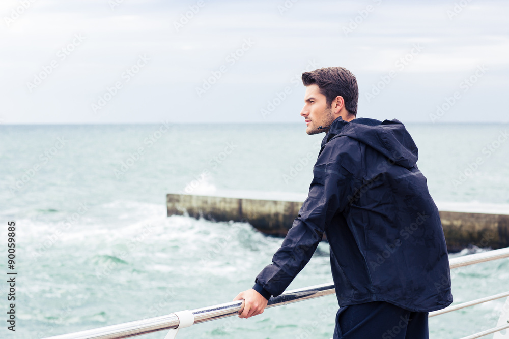 Man in sports wear standing near sea