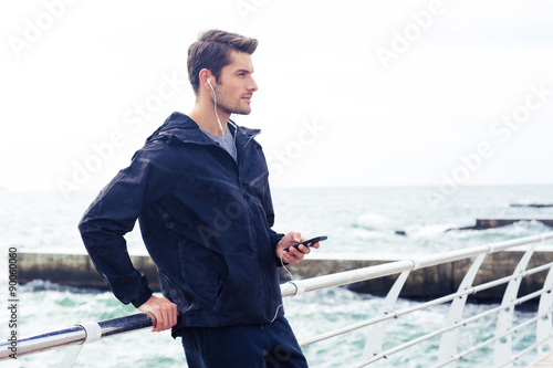 Man listening music on smartphone outdoors