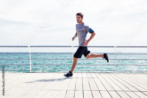 Sports man running outdoors near sea