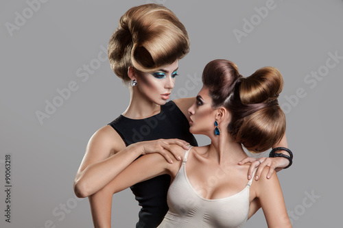 Studio photo of two beauty women with creative hairstyle looking