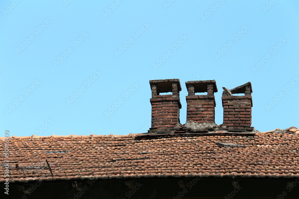 Naklejka premium Brick chimney on tile roof of an old wooden house