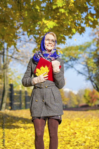 Happy young woman and red book in autumn park
