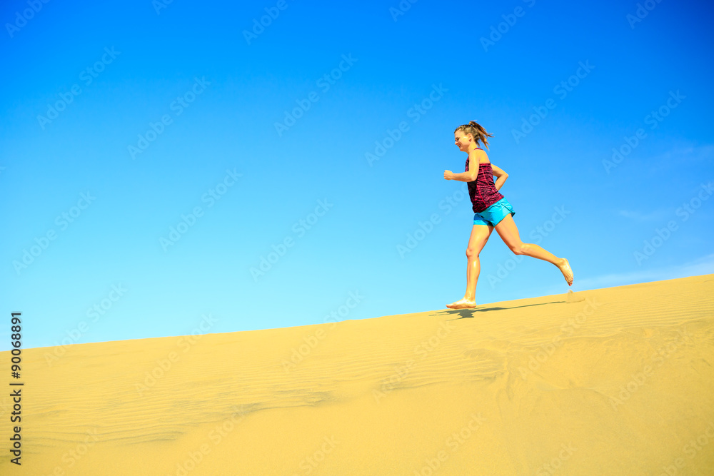Young woman jogging barefoot on sand desert dunes Young woman jogging barefoot on sand desert dunes