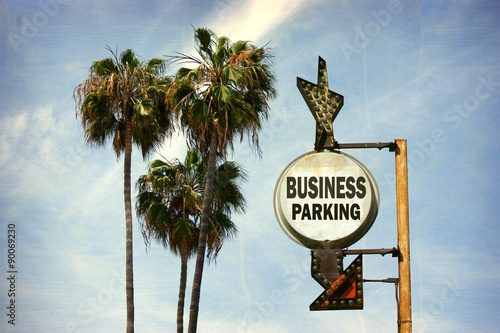 aged and worn vintage photo of business parking sign with palm trees