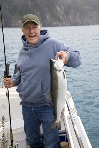 Happy fisherman in Alaska holds big silver salmon
