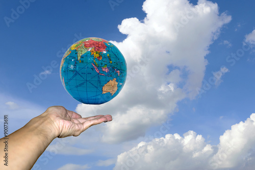 Fototapeta Naklejka Na Ścianę i Meble -  Hand holding globe model on beautiful blue sky with clouds in the clear day.