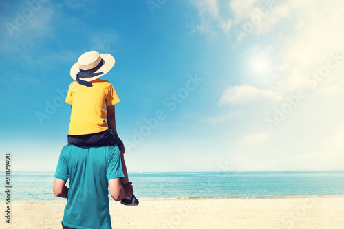 Father carrying son on his shoulder wolking on beach photo