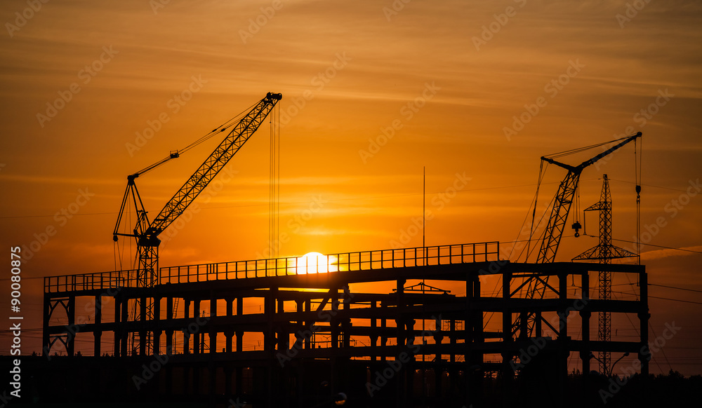 cranes and buildings under construction against the setting sun