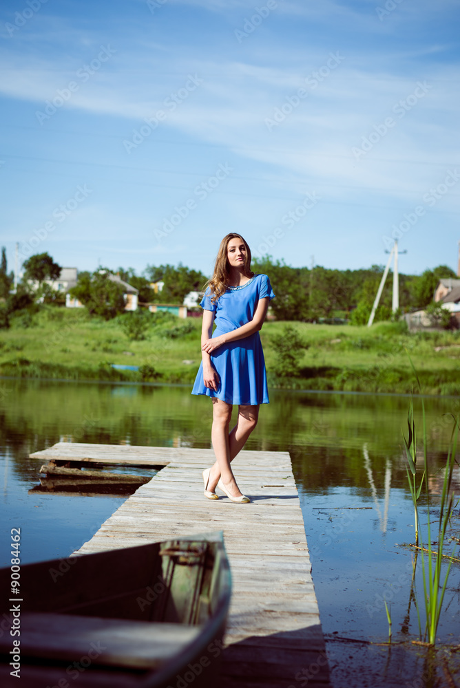 Relaxing brunette young pretty girl in blue dress on bridge