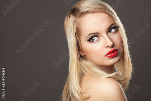 Fashion Stylish Beauty portrait of smiling beautiful blonde girl with professional make-up, false eyelashes and red lips in photostudio