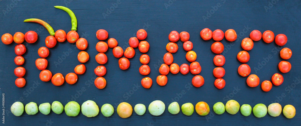 Word tomato written with green and red tomatoes on wooden backgr Word tomato written with green and red tomatoes on wooden backgr