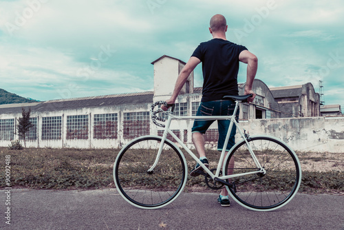 Young man with a fixie bike. Decadent industrial setting